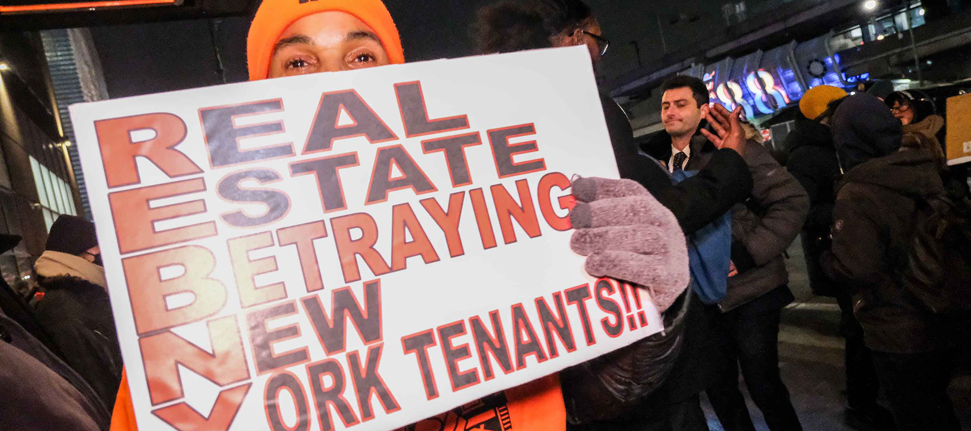 Person raising a sign saying ‘Real estate betraying New York tenants.’