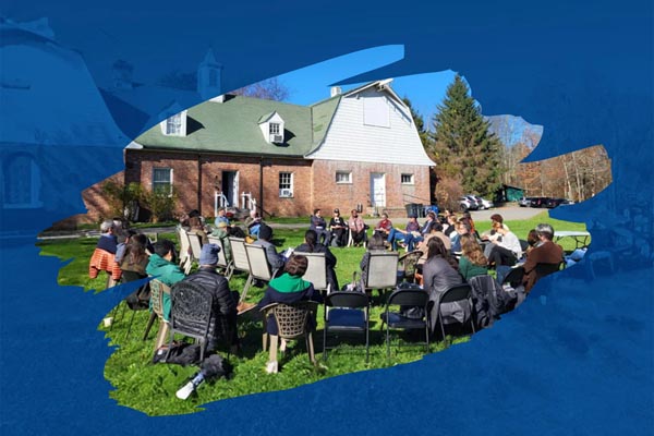 Outdoor circle gathering on a lawn in front of a brick house framed by abstract blue shapes