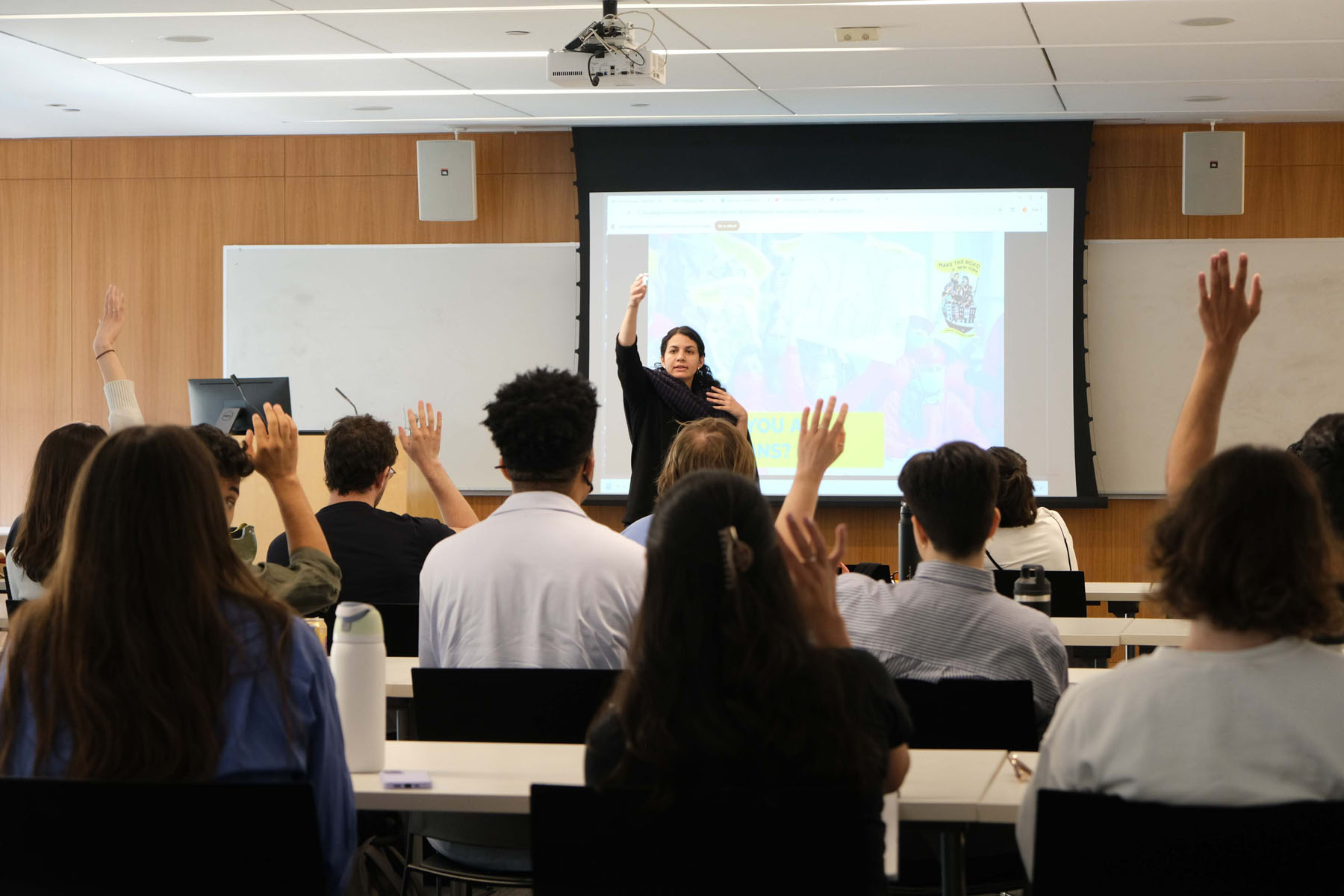 Classroom of students raising their hands as an instructor leads a discussion
