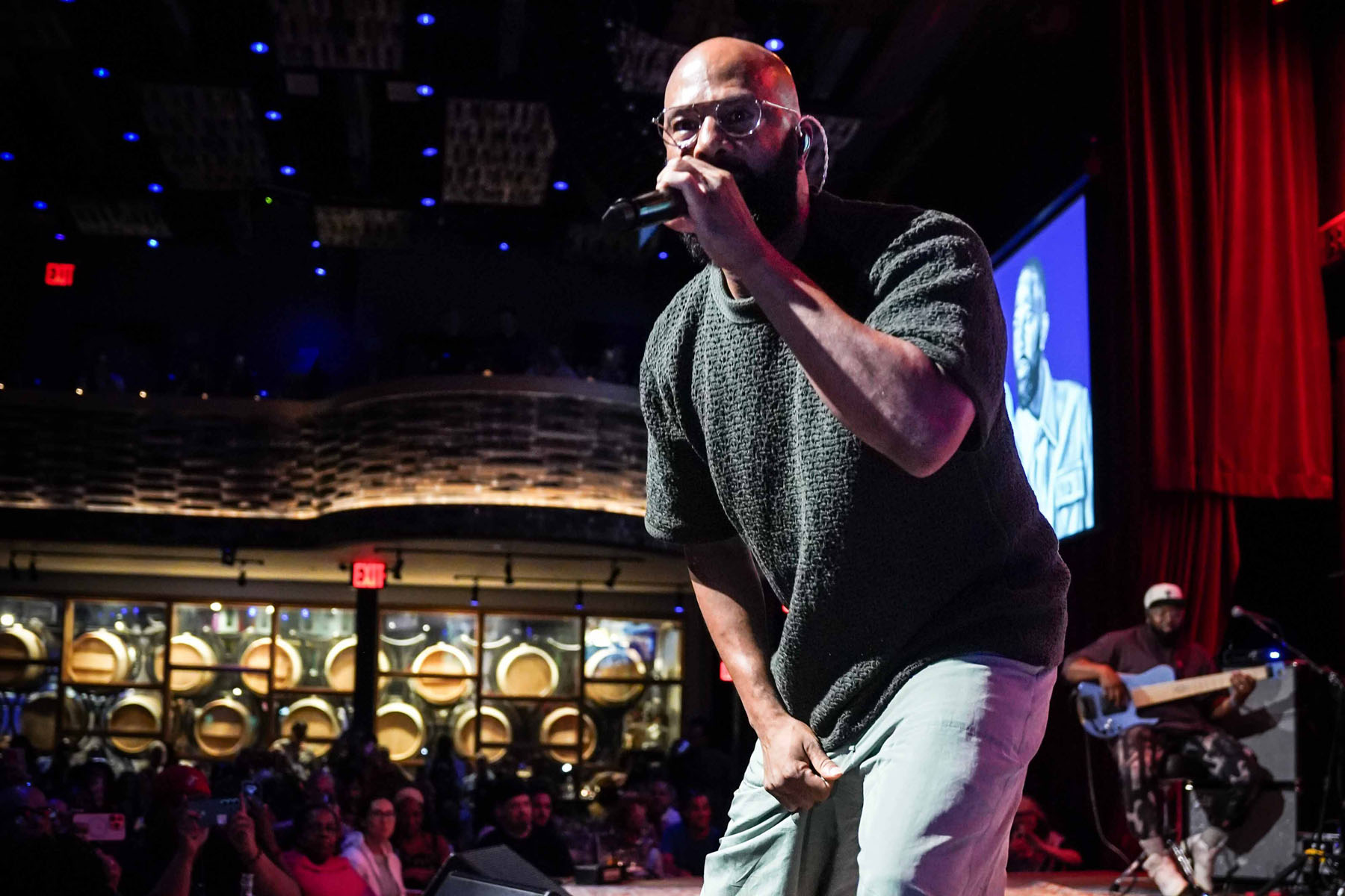 Performer rapping onstage before a lively audience in a dimly lit venue
