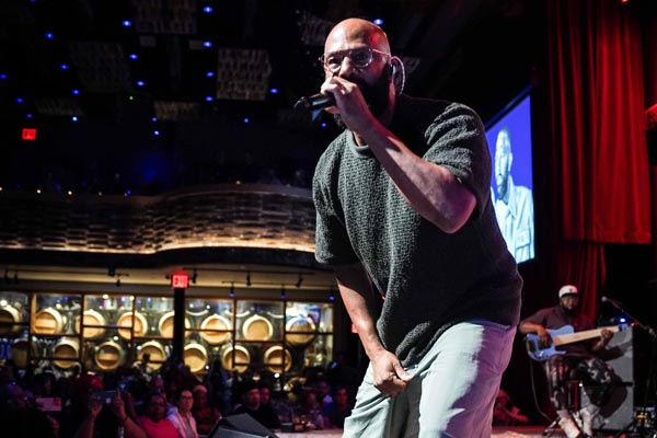 Performer rapping onstage before a lively audience in a dimly lit venue