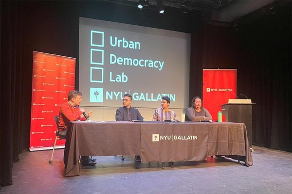 Panelists speak onstage at NYU Gallatin beneath a screen reading “Urban Democracy Lab.”