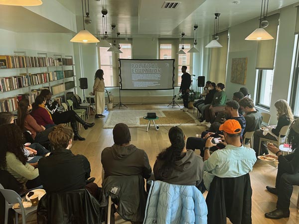 Participants sit in a circle for a political education session with a projected presentation.