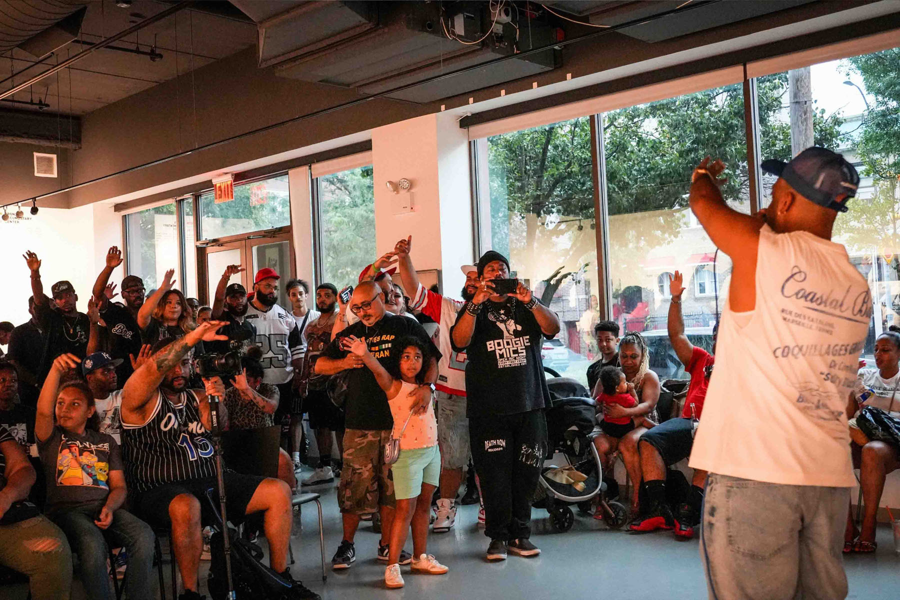 Crowd cheering inside a community space as a performer gestures toward them
