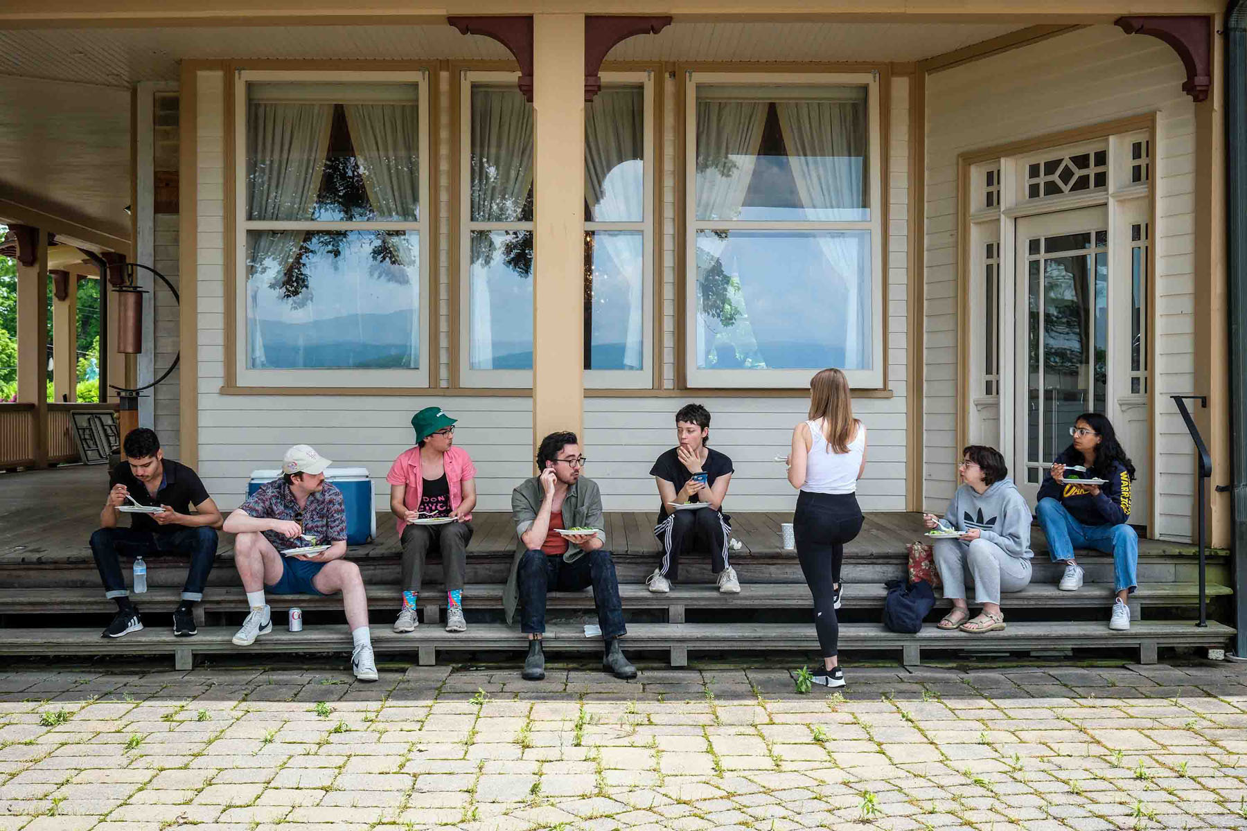 Law students sitting on porch steps eating lunch and having a conversation.
