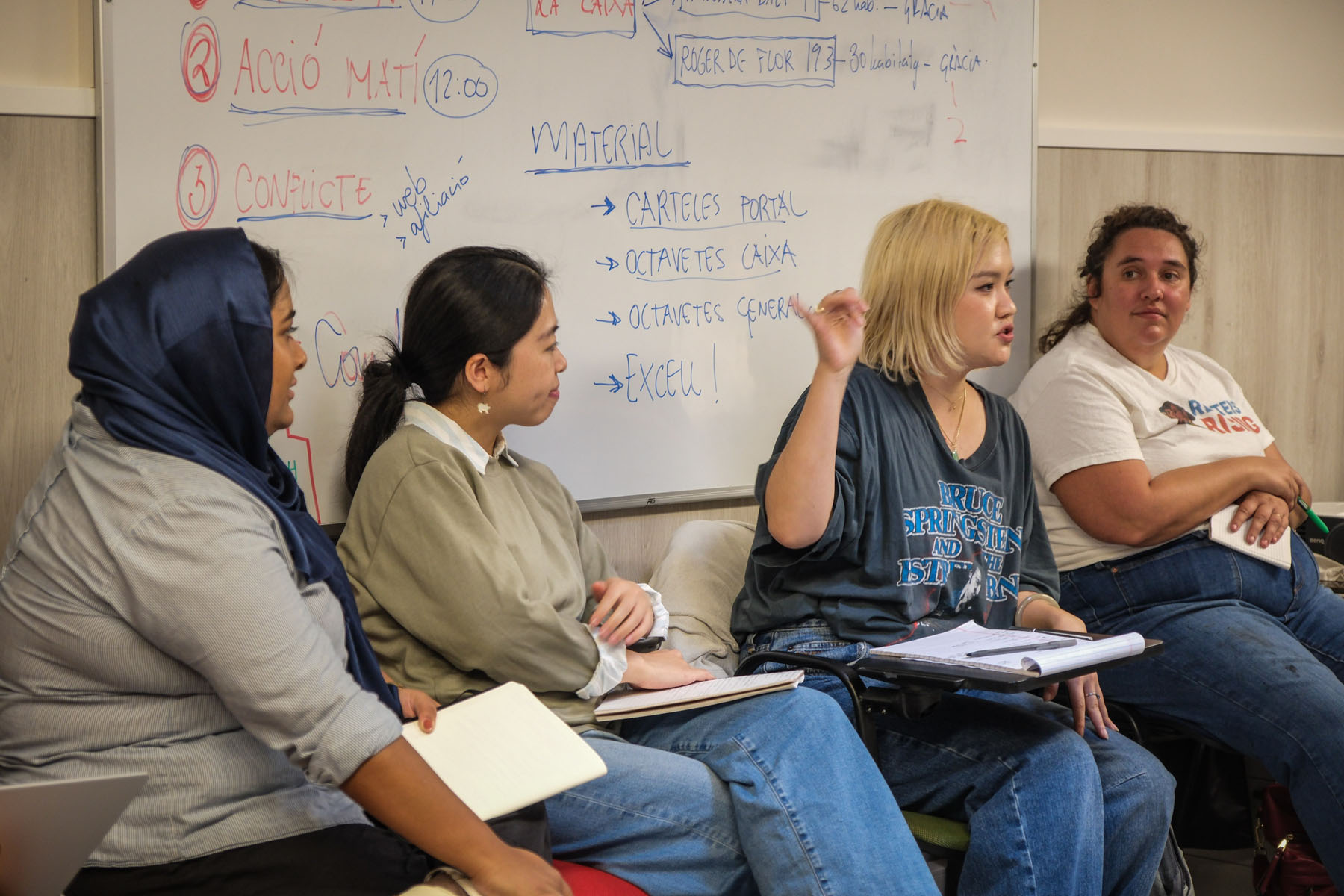 Participants seated in a workshop discussion with notes written on the whiteboard behind them