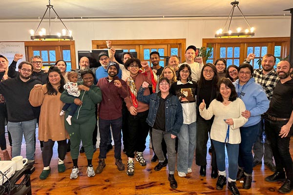 Large group poses indoors with raised fists during a gathering or workshop.