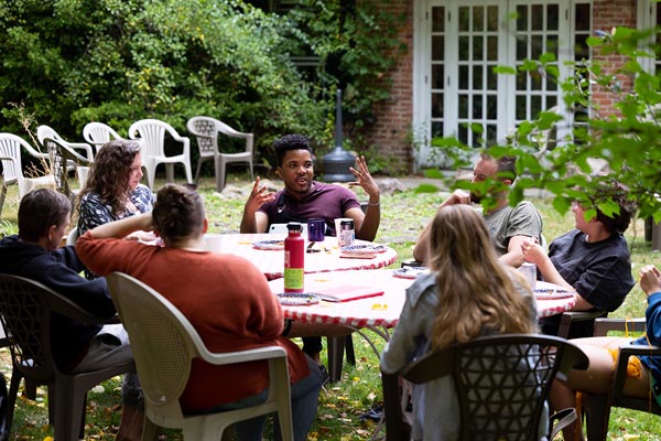 A group of people seated outdoors around a table having a discussion.