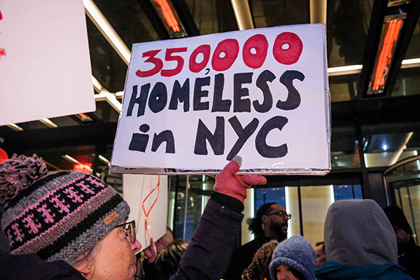Protester holding a sign reading ‘350,000 homeless in NYC.’