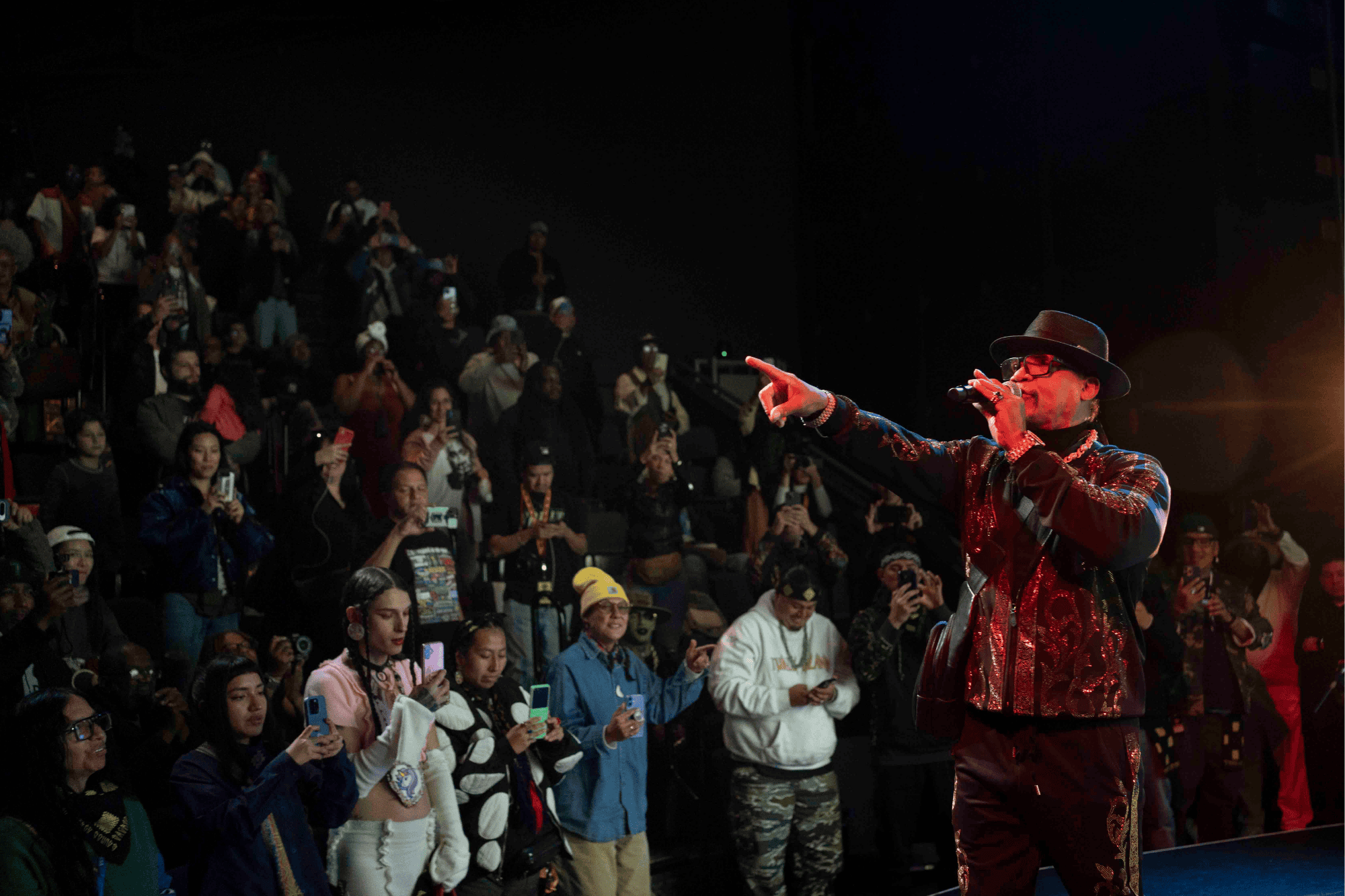 Performer with mic pointing at audience from the stage.