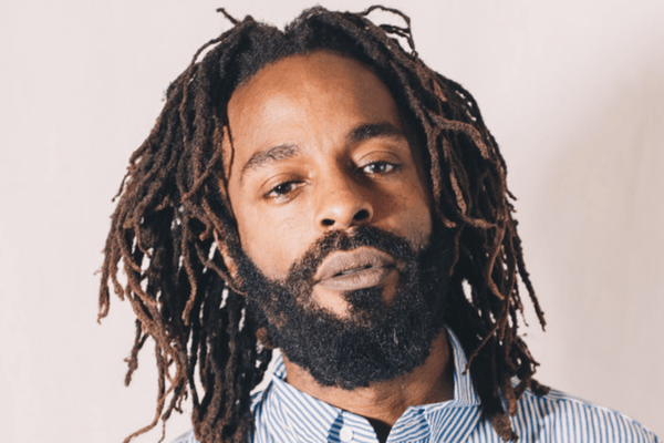 Headshot of John Forte, African American man with short locks and wearing a blue and white striped oxford shirt.