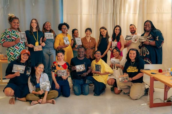 A group of people smiling and holding up photographs.