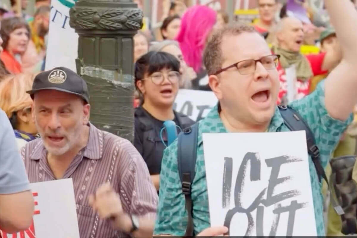 Two men shouting and holding protest signs at a demonstration.