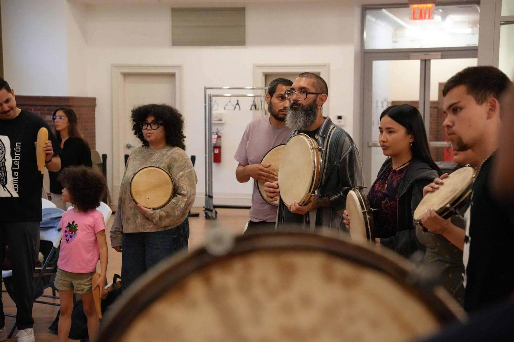 Group of people standing and holding hand drums.