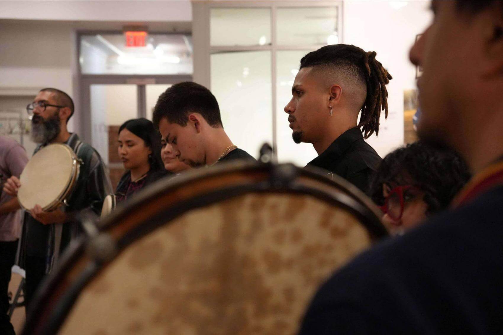 Four people standing in a room holding hand drums.