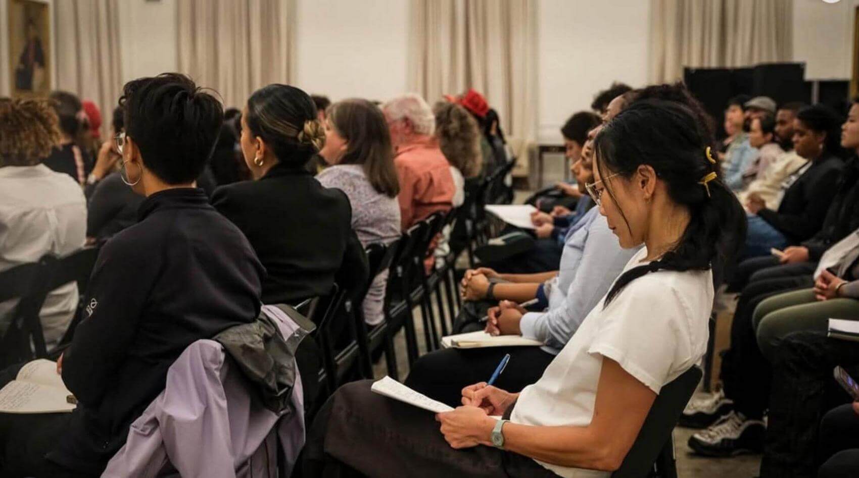 A panel discussion with four speakers seated on a stage, one speaking into a microphone.