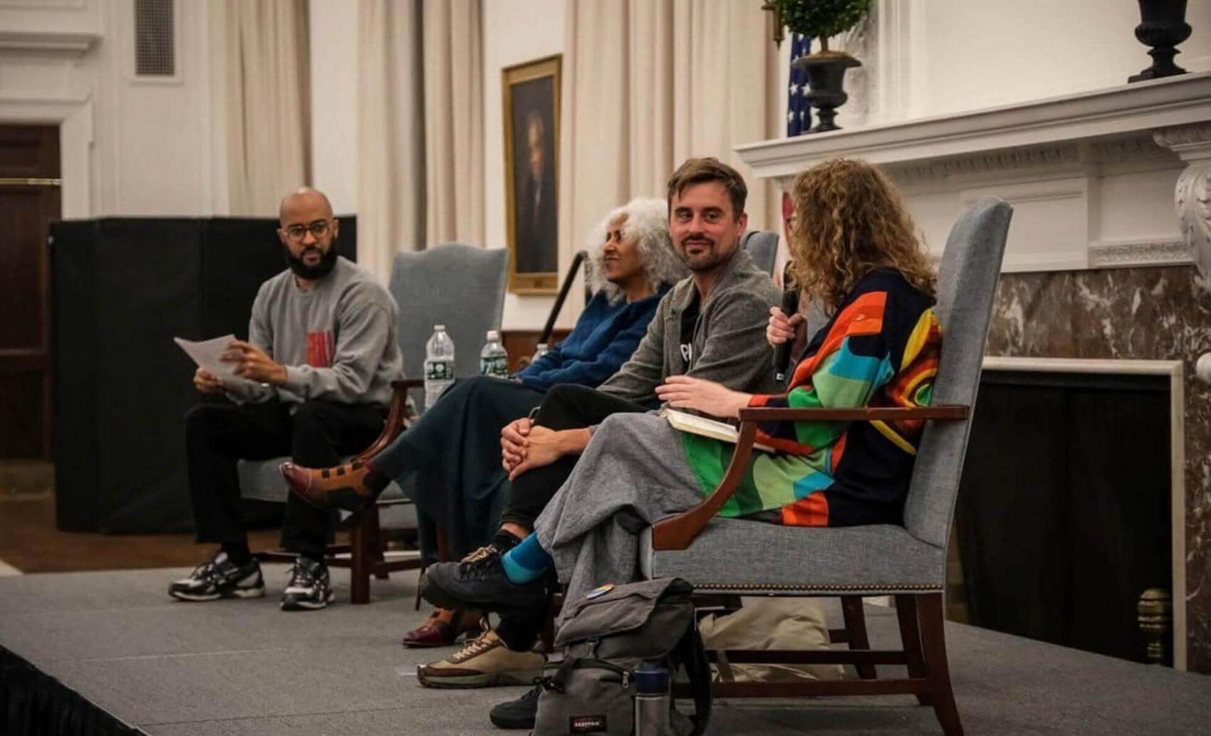 Group of people sitting in chairs, focused on a speaker or presentation, with some taking notes.