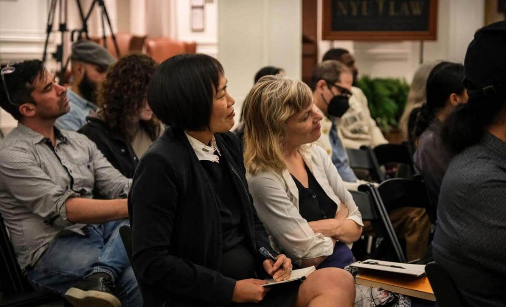 Audience of various individuals seated in a room, focused on a presentation at NYU Law.