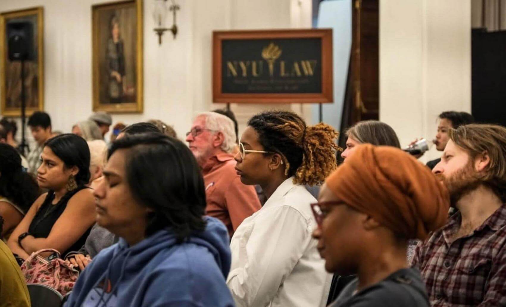 People seated in rows, taking notes during an event or lecture.