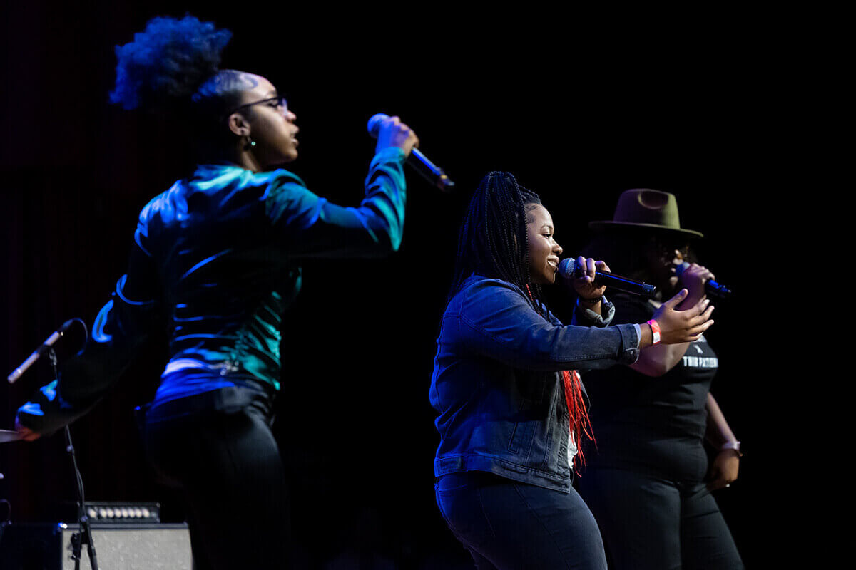 Two performers singing on stage at an event.