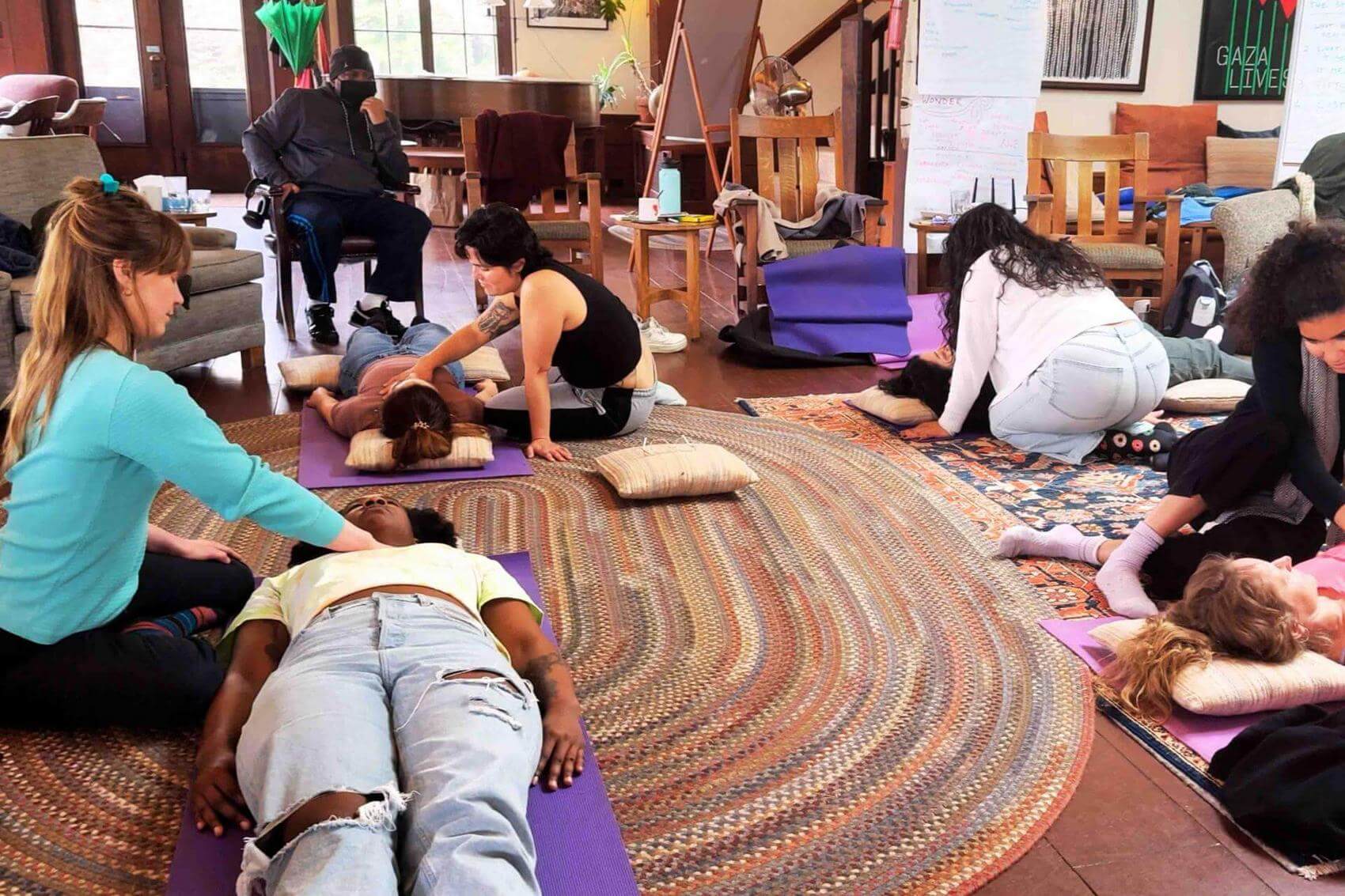 A group of people practicing bodywork on mats.