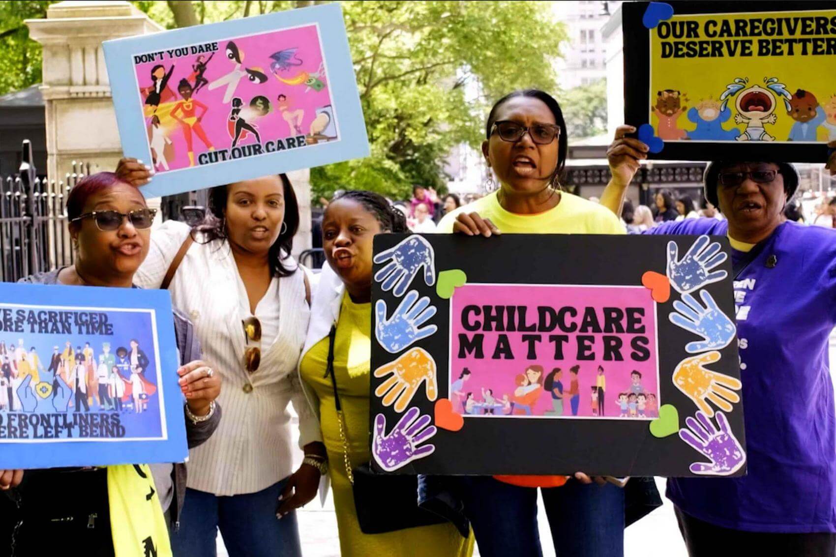 Protesters hold signs demanding free childcare and social services.