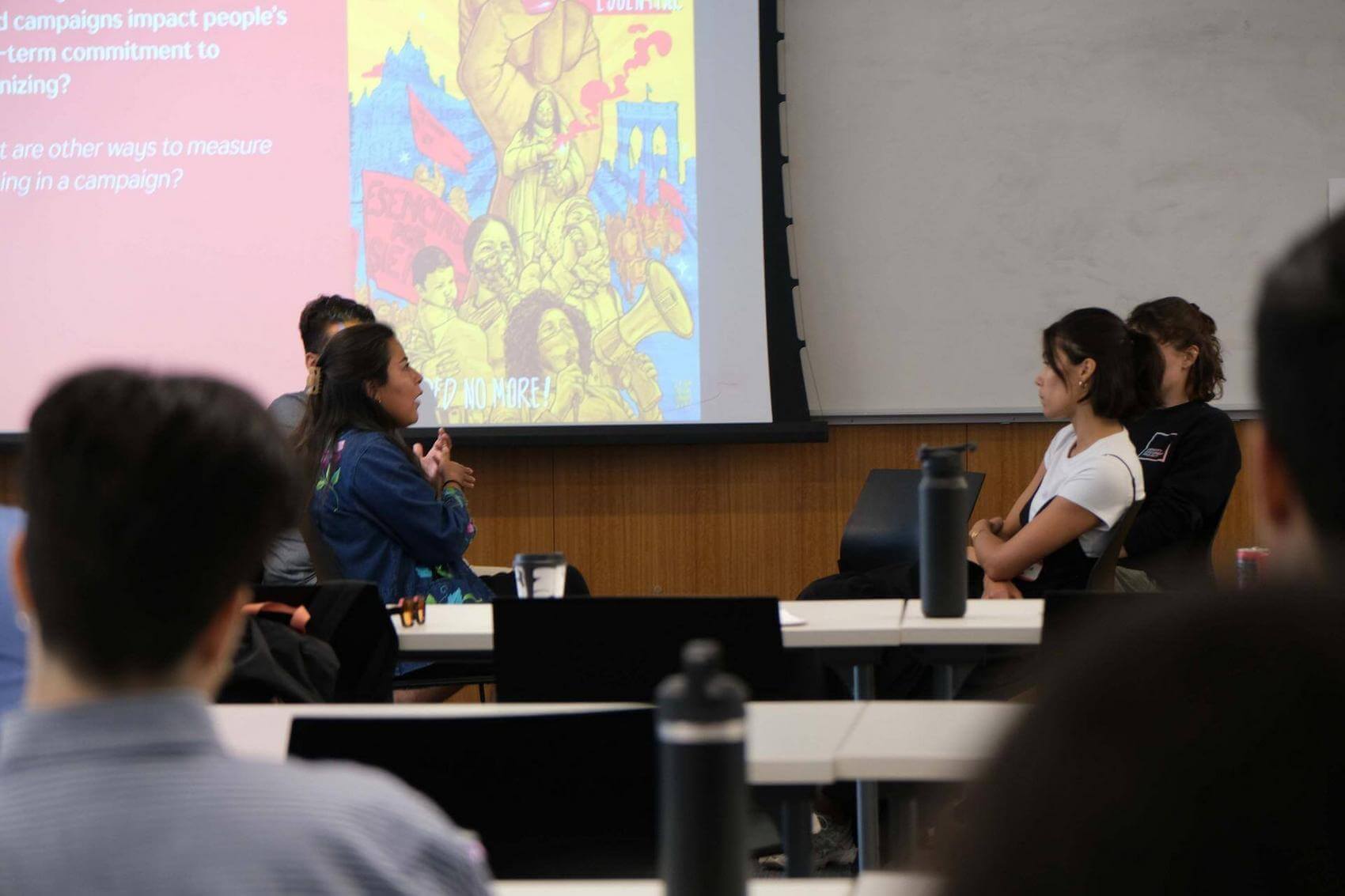 People sitting at a table with drinks, taking notes in notebooks.