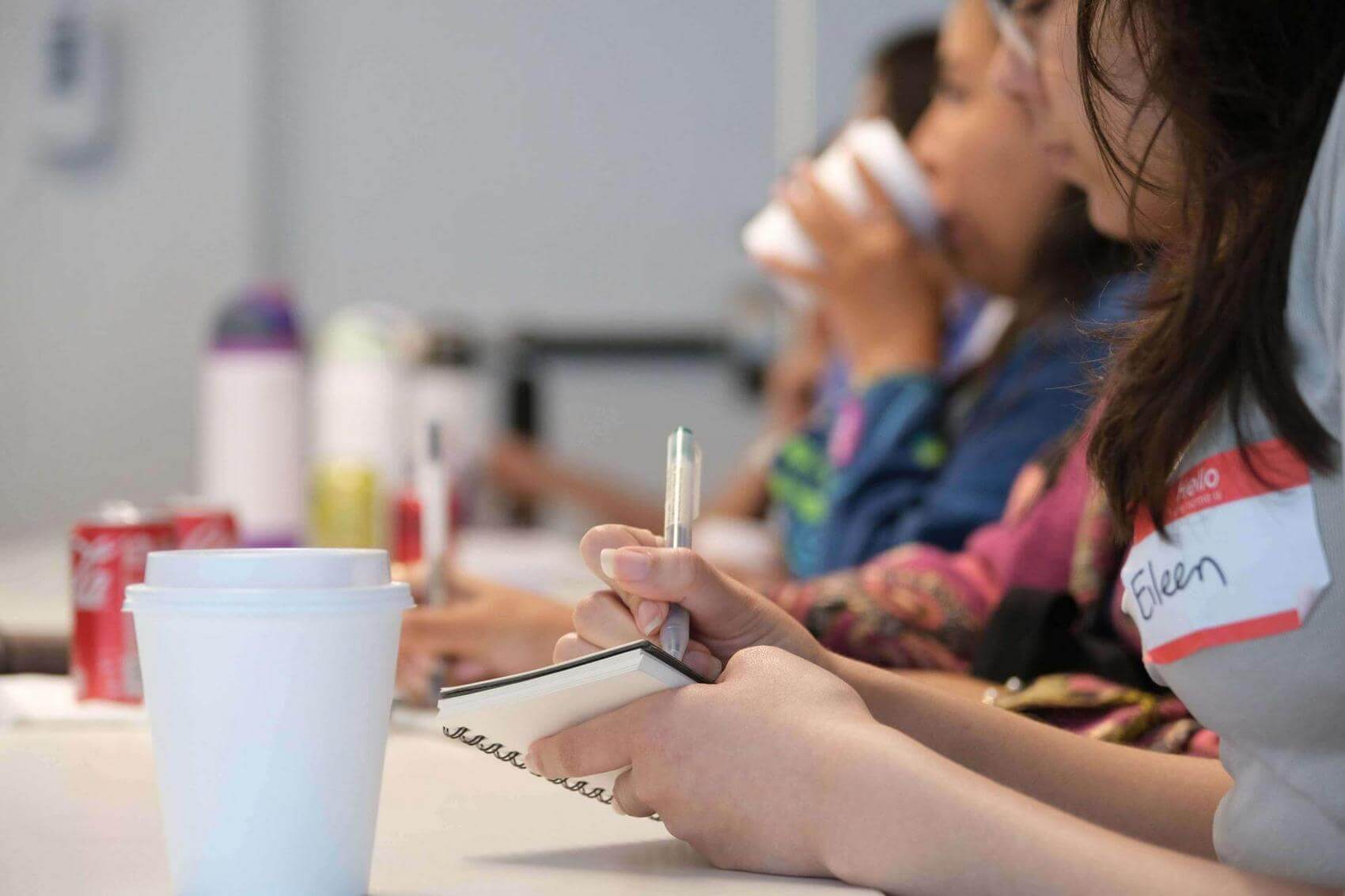 People sitting at a table, clapping, with drinks and snacks in front of them.