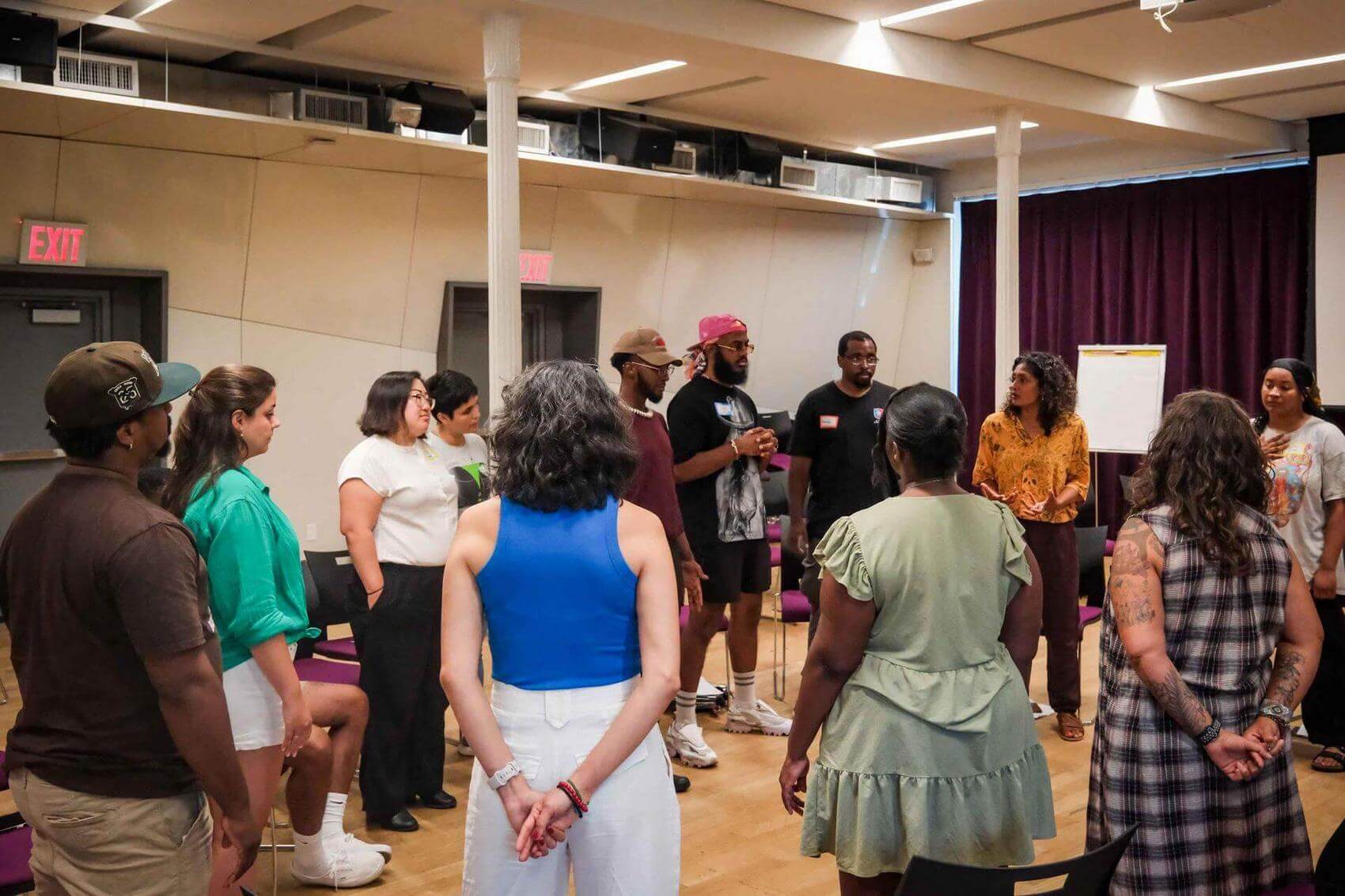 A speaker gestures while addressing a seated group in a classroom setting.