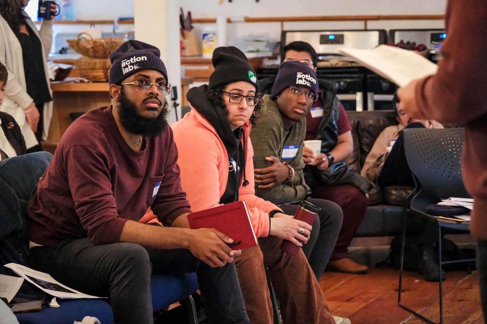 Two women dance in a room with musicians playing drums and a microphone nearby.
