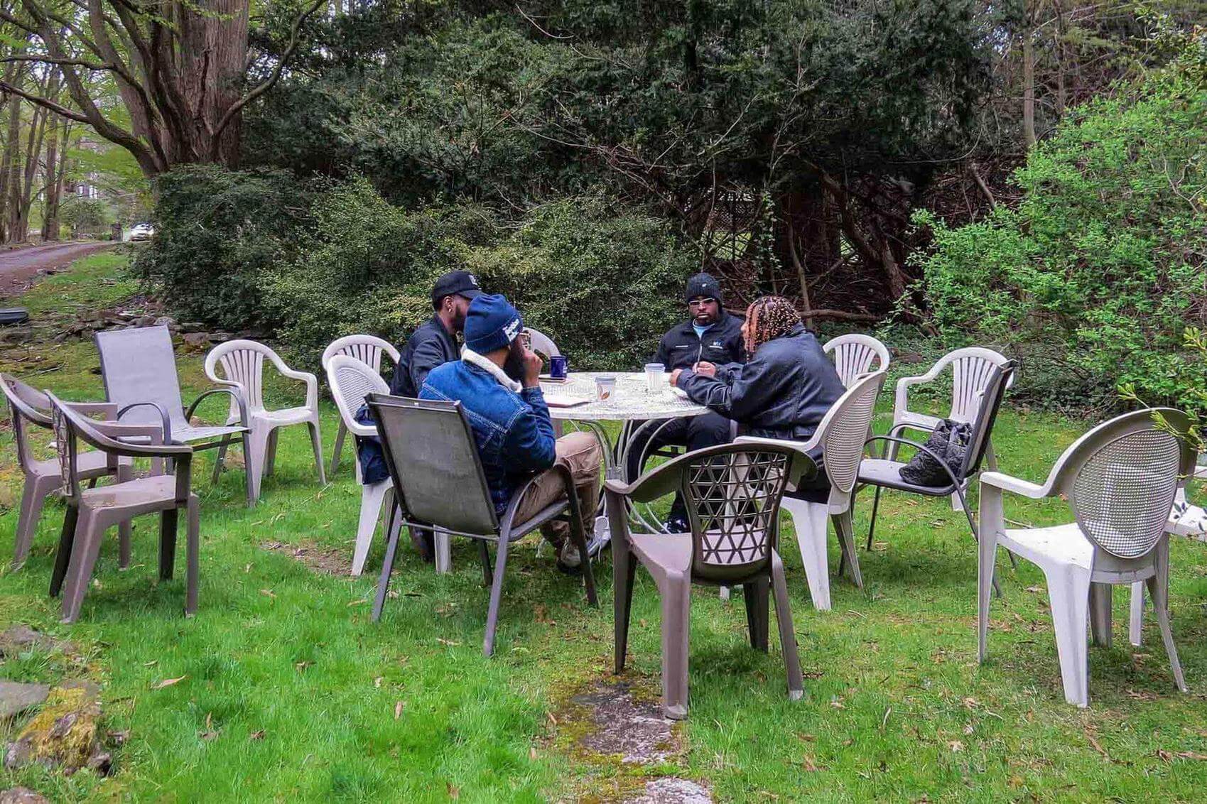 A group of people sitting at a wooden table, clapping and smiling during a gathering.