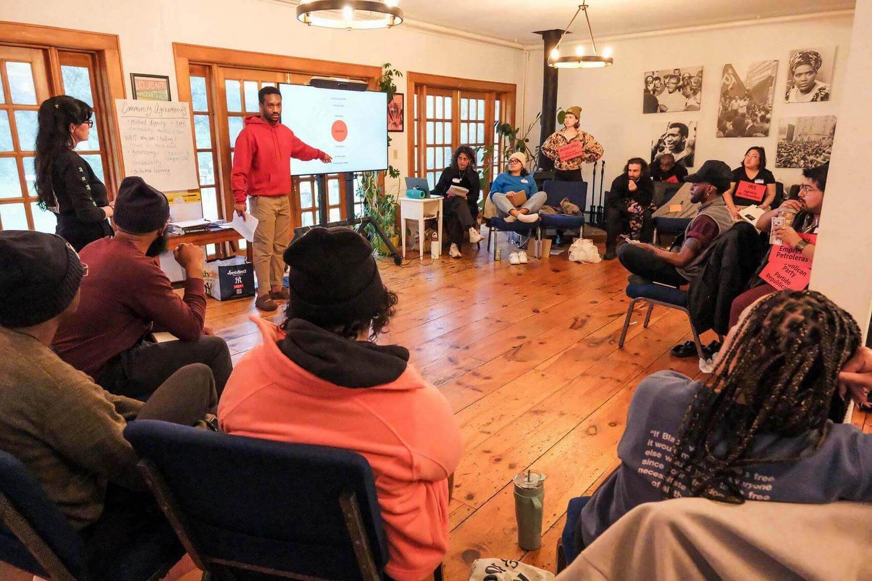Group of five people seated at a circular table in a grassy area, engaged in conversation.