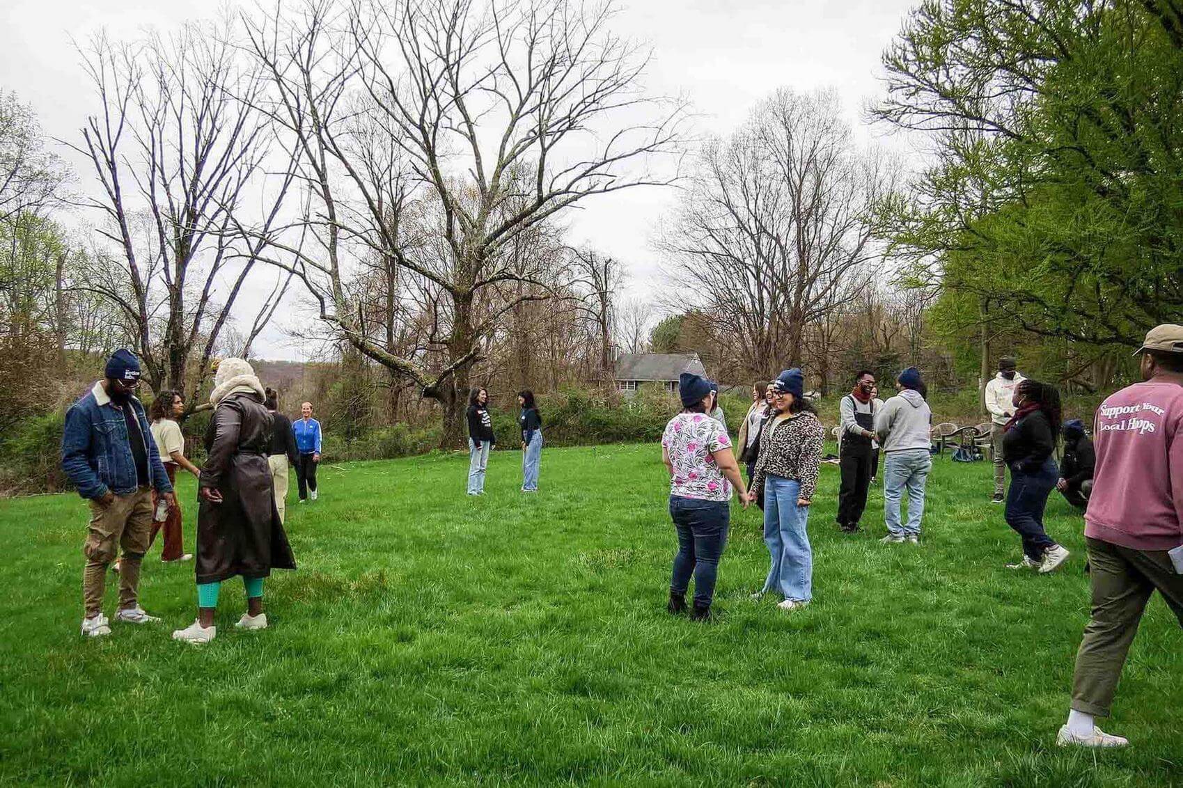 Three people at a table laughing while playing a card game, with others in the background.