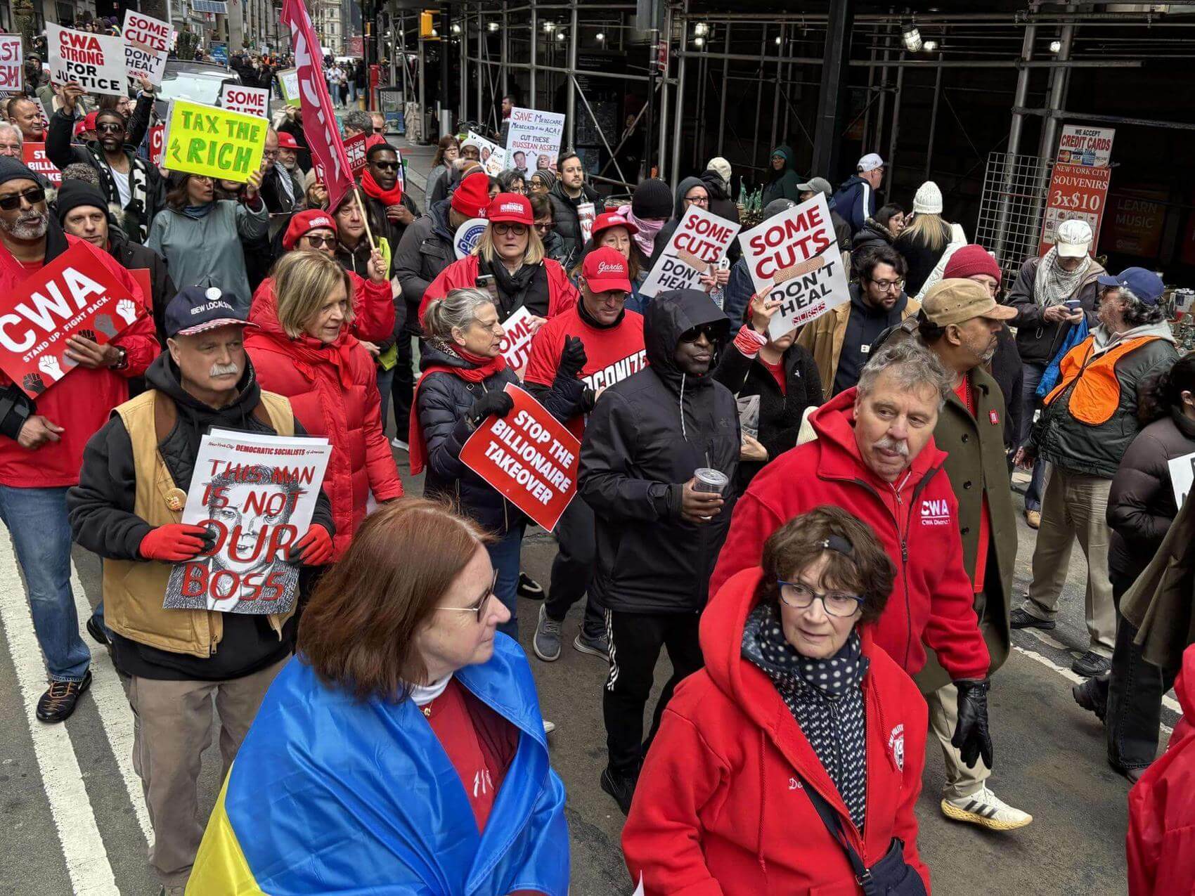 Protesters hold signs shaped like tombstones, denouncing various social issues.