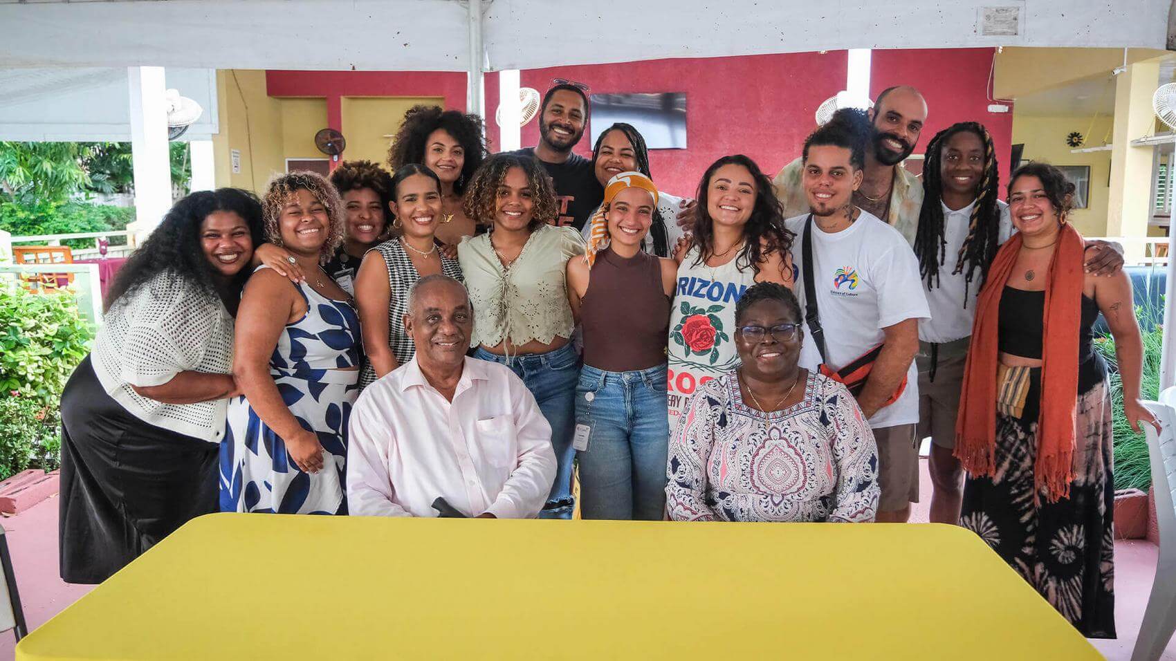 A group of six people engage in conversation indoors, with one woman laughing.