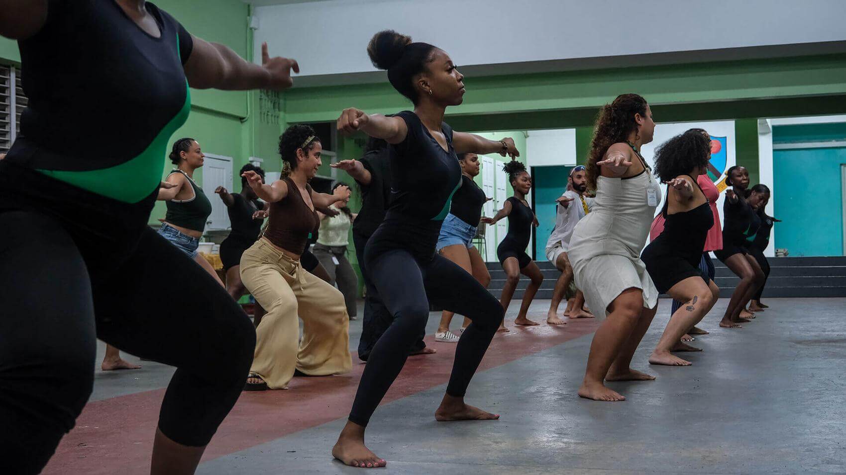 A woman laughs while writing in a notebook; a man watches her with a smile.