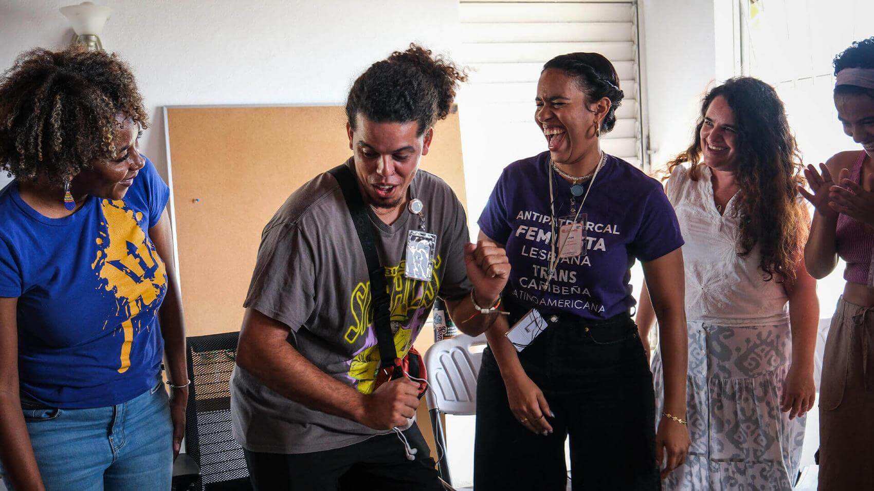 Three people playing drums outdoors at night, surrounded by greenery.