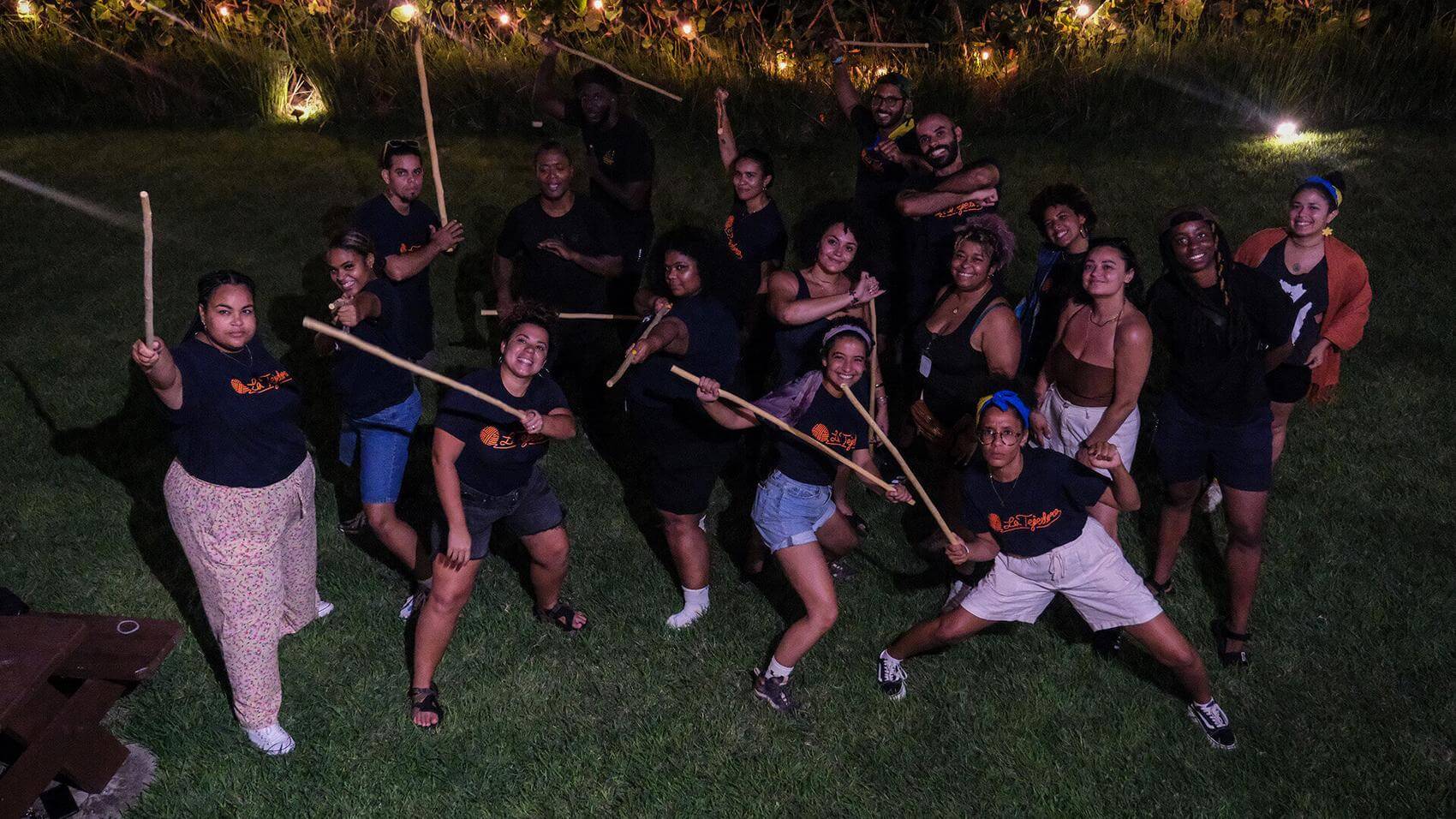 Group sitting in a circle on the beach, engaged in conversation under trees.