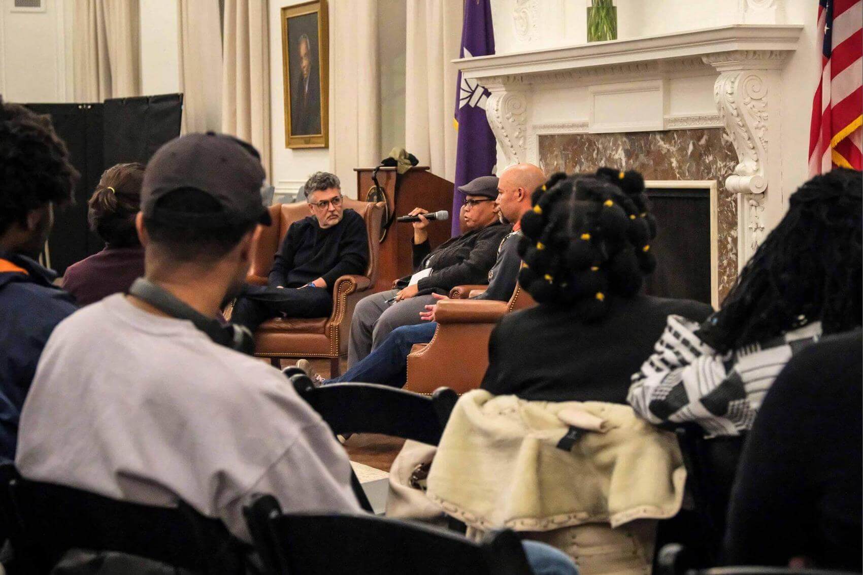 Person seated in a leather armchair, raising a fist while holding a notebook and pen.