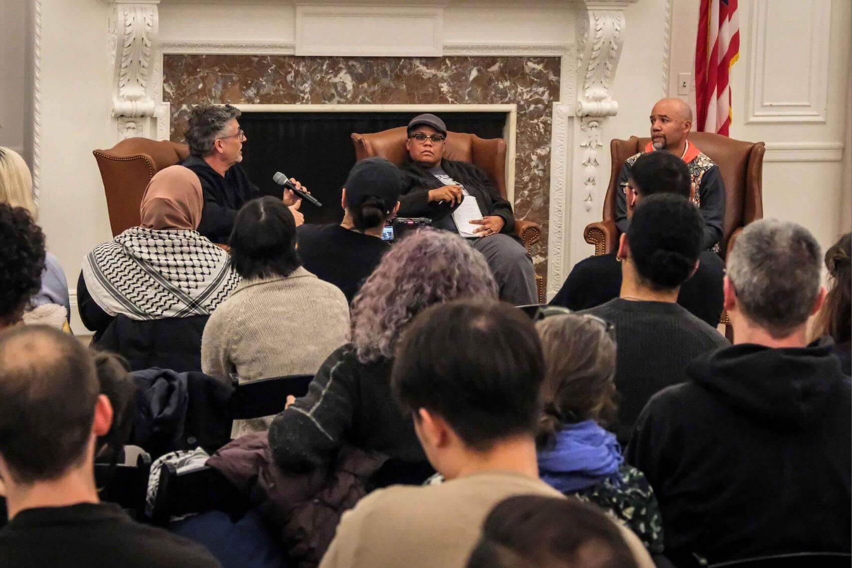Audience members seated and focused during an event, some taking notes.