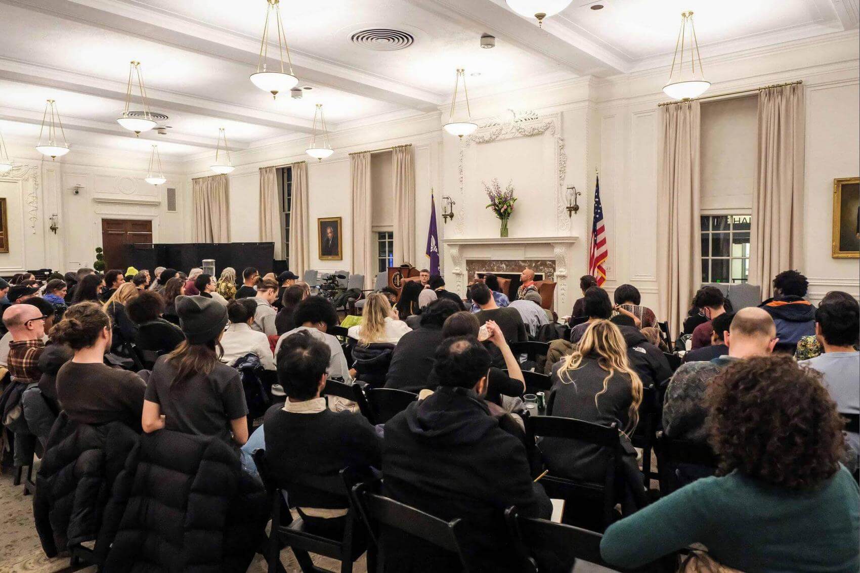 Discussion panel with three speakers seated in armchairs, audience members in foreground.