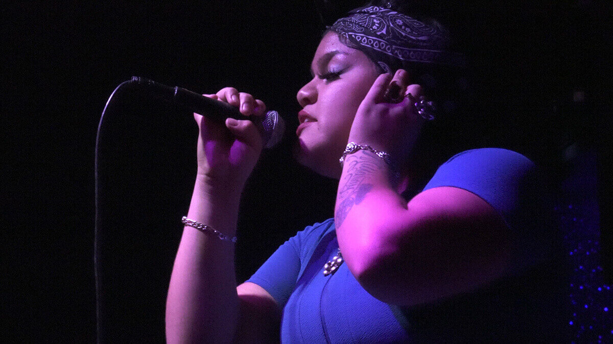 Person holding a microphone close to their mouth while adjusting an earpiece.