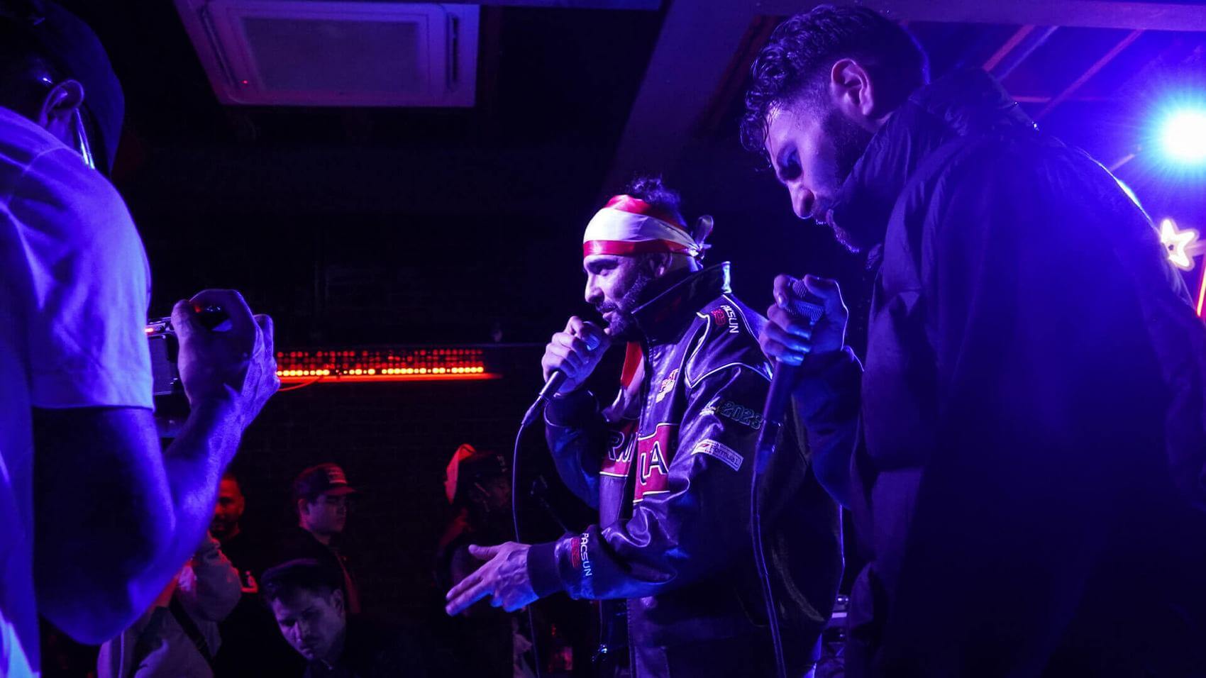 Two men pose for the camera; one shows a drawing of the other, who is making a fist.