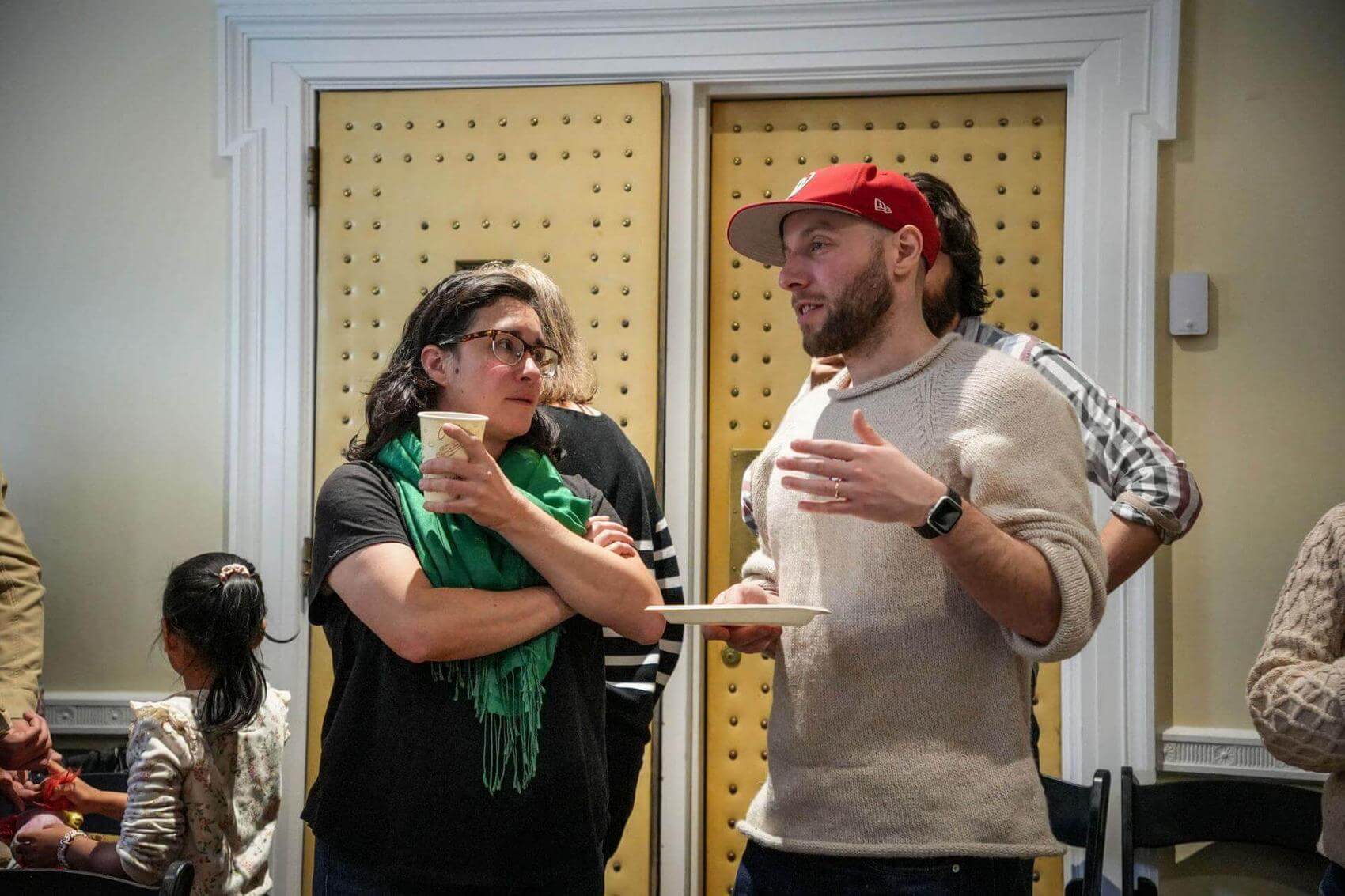 Three people engaged in a discussion at a table with notebooks and drinks.