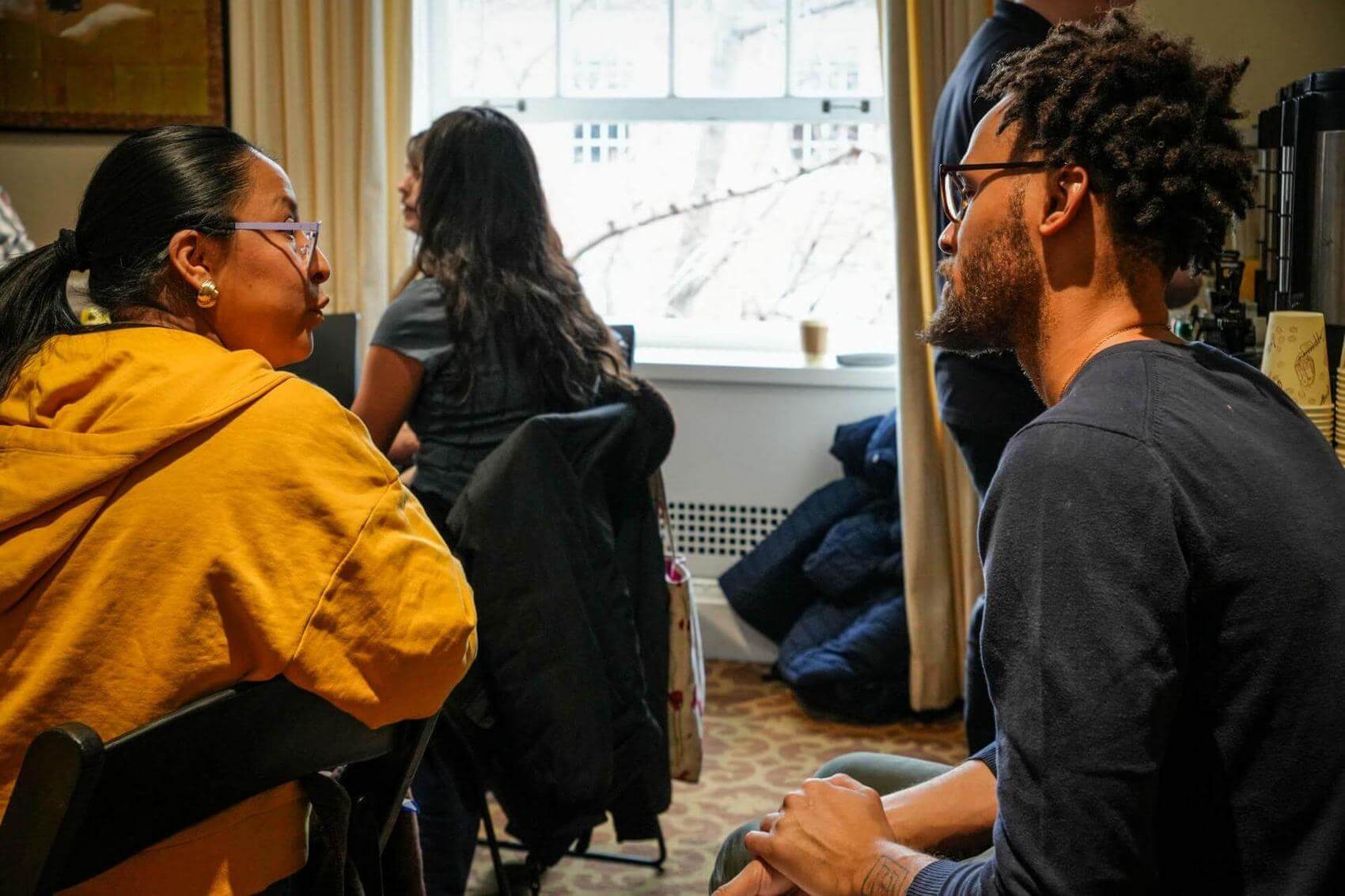 Group discussion around a table with people engaged in conversation and writing.
