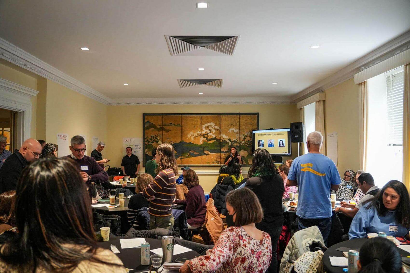 Group of people at a table sharing a laugh, with food and drinks visible.