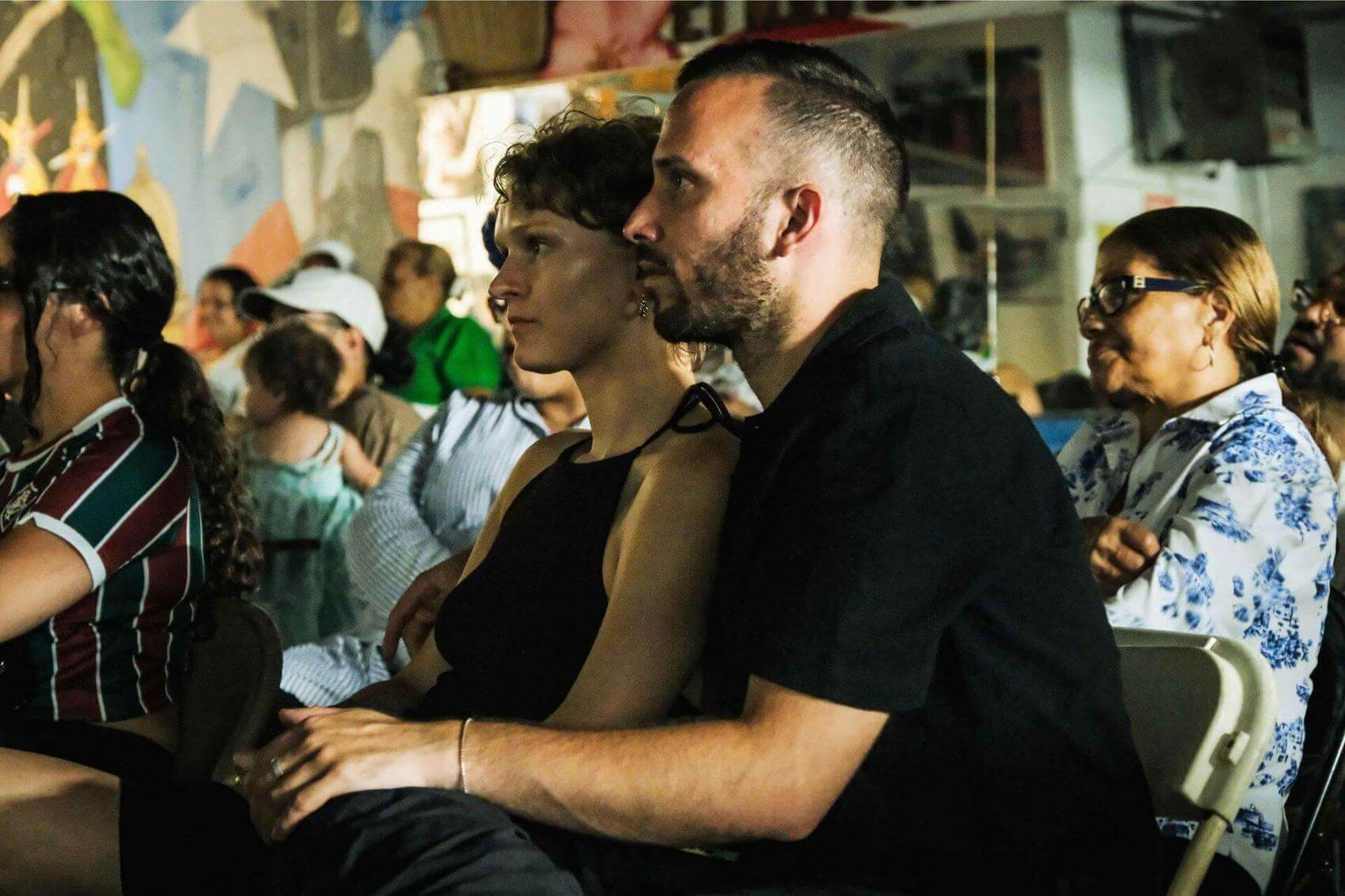 People sitting and clapping in an indoor event or meeting.