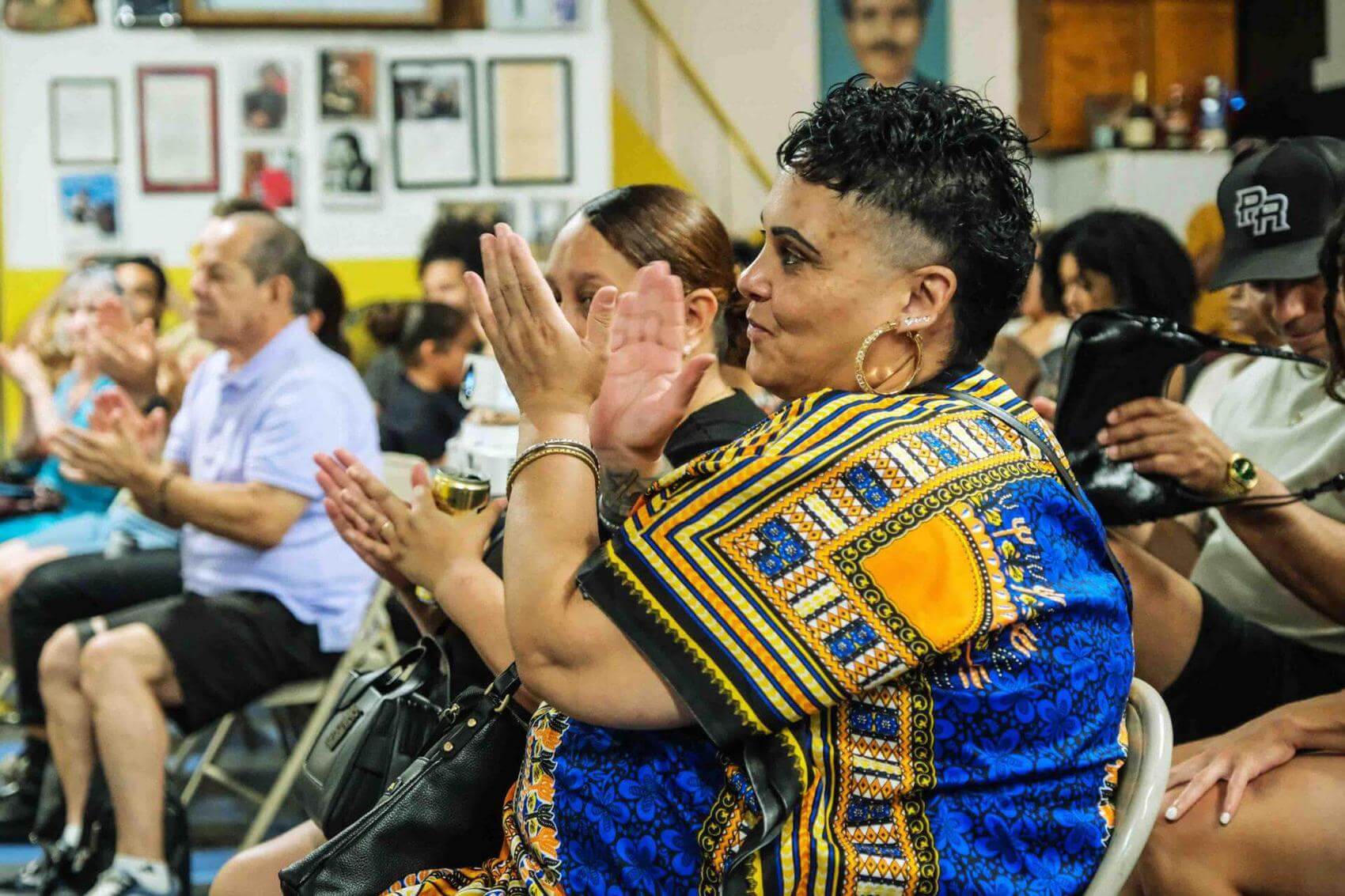 Audience watching a film on a large screen, with a speaker at a table in the foreground.