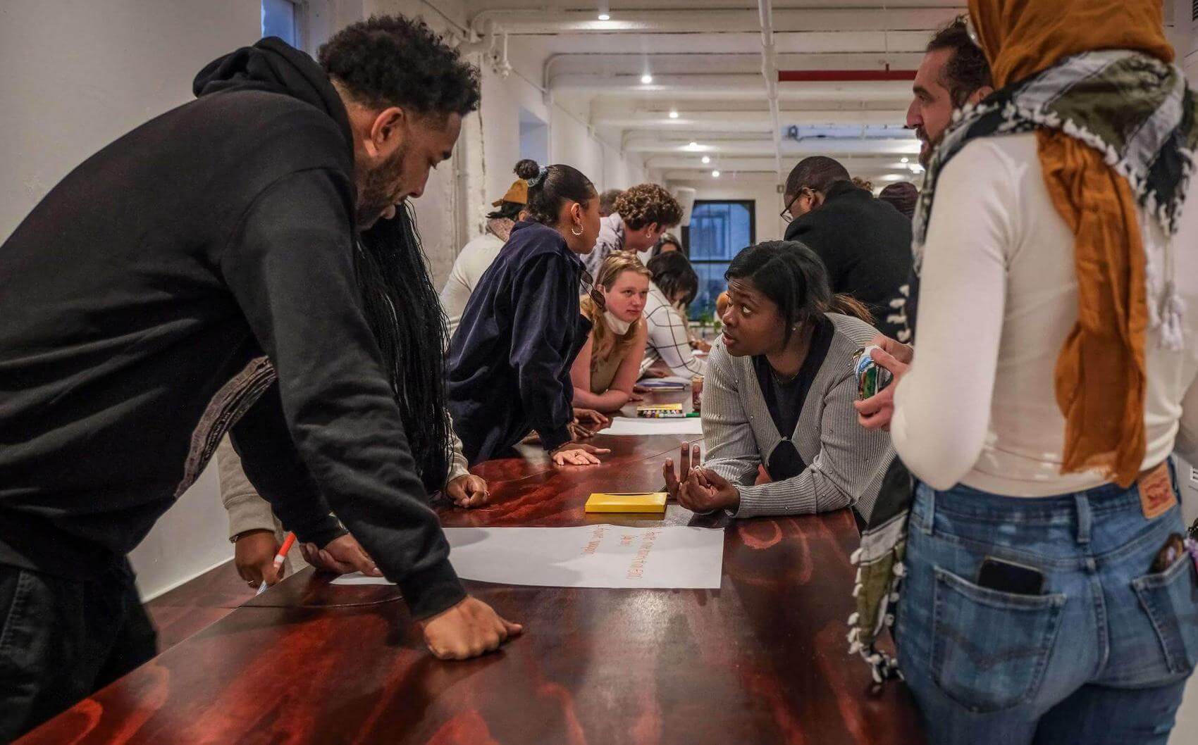 Group of people sitting in a circle in a room, engaging with a speaker and presentation.
