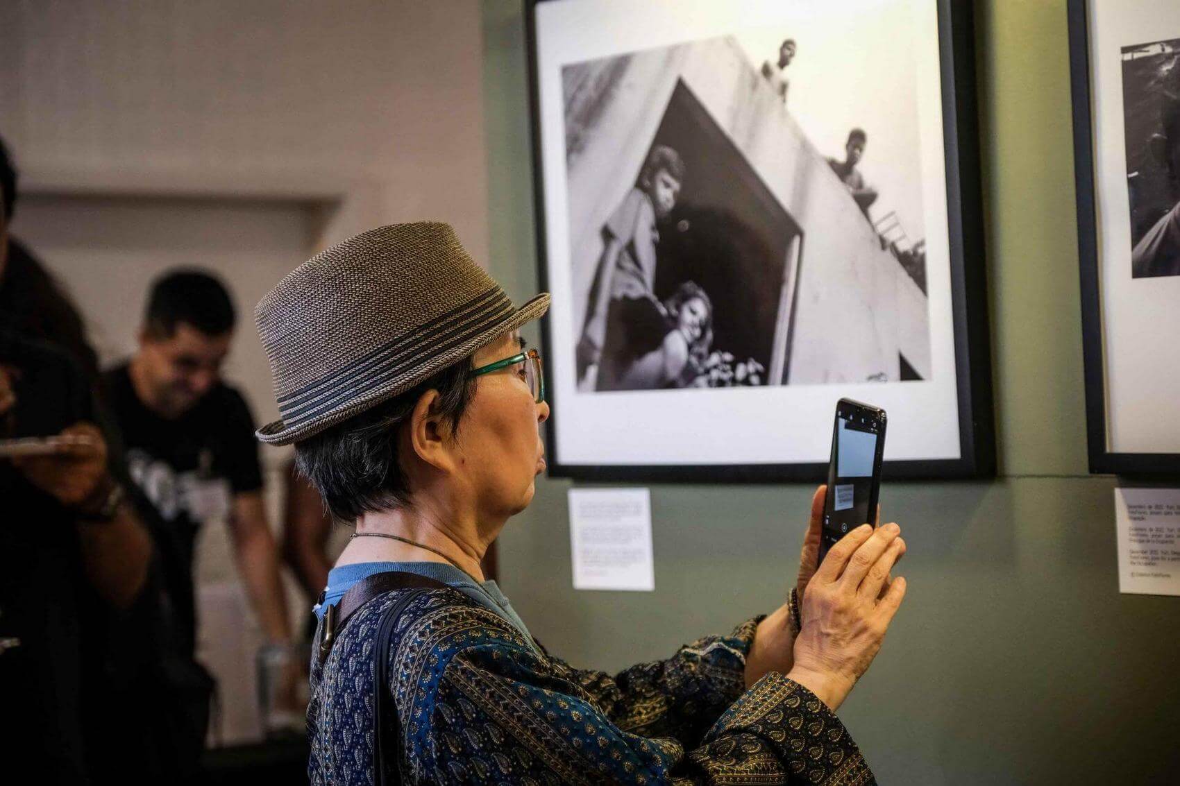 Man smiling while using headphones connected to a phone mounted on the wall.